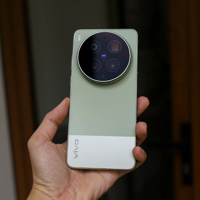 A hand holds a light green and white smartphone.